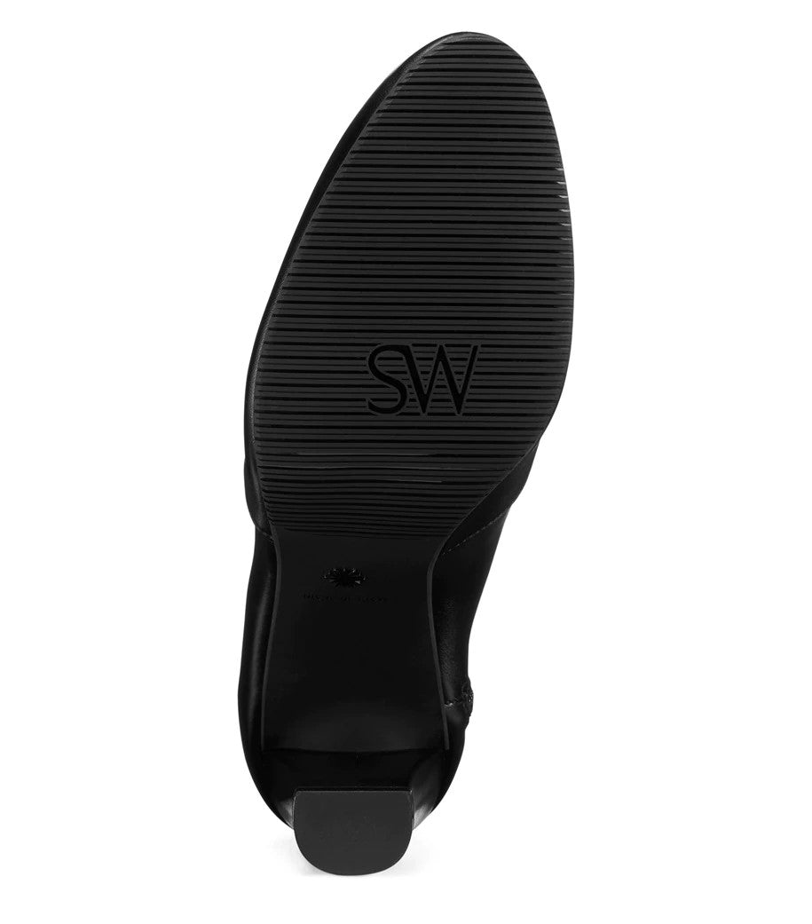 View of sole of glossy black leather boot. Brand name SW is written on the sole. 