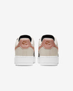 Load image into Gallery viewer, Rear view of Nike shoe. Has white midsole, pink Nike Air inscription and is made of beige leather.
