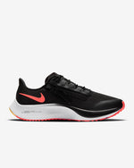 Load image into Gallery viewer, Side view of black Nike running shoe. Has black laces, white midsole and an inverted orange Nike logo. 
